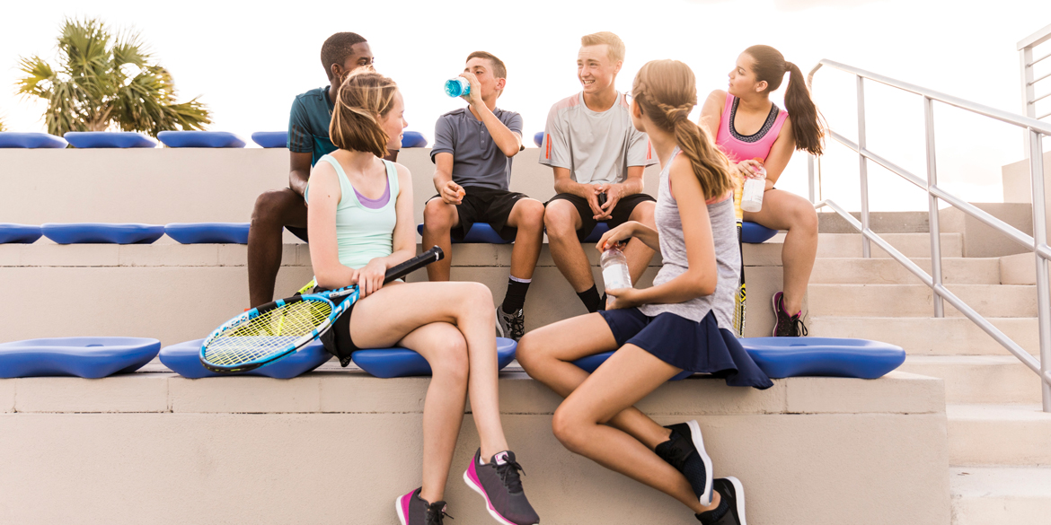 Teen athletes sitting on a stand talking