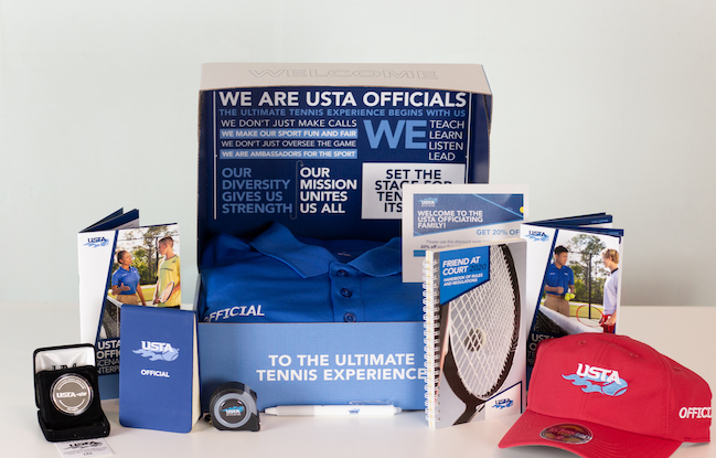 Welcome package for tennis officials including a hat, collared shirt, notebooks, and other various tools.
