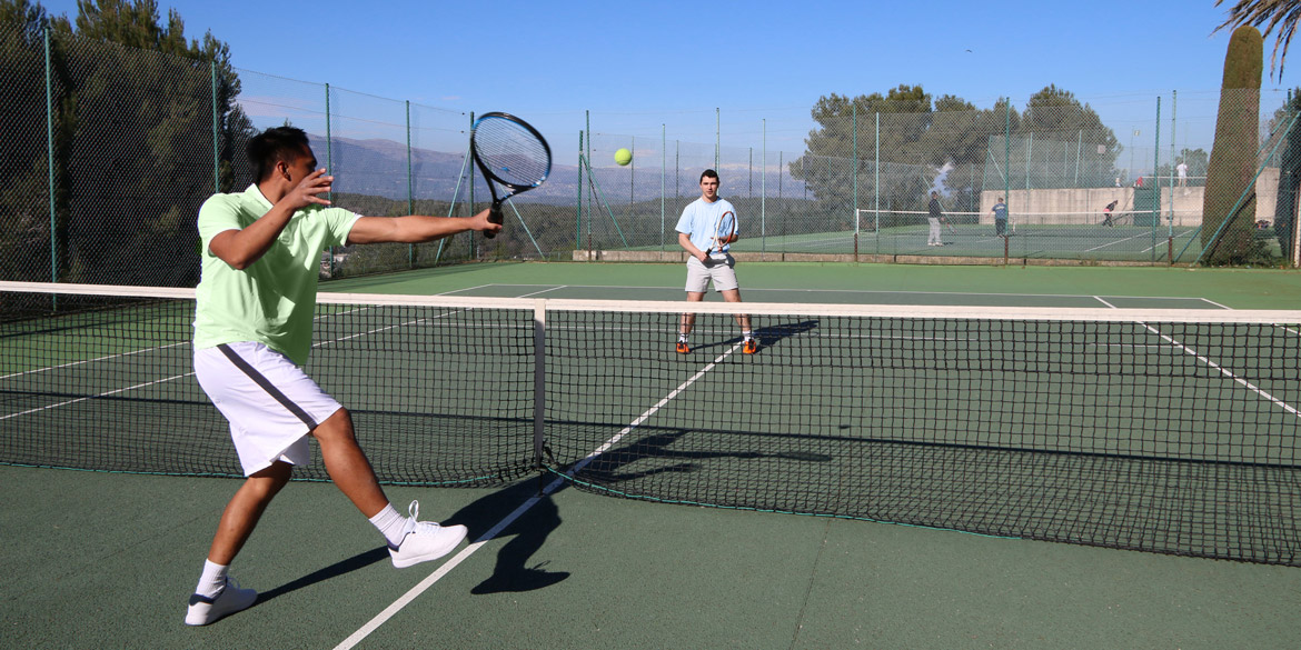 Two male tennis players hitting a tennis ball to each other.
