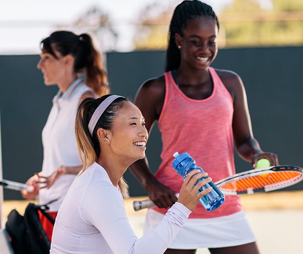 Women drinking water on a tennis court