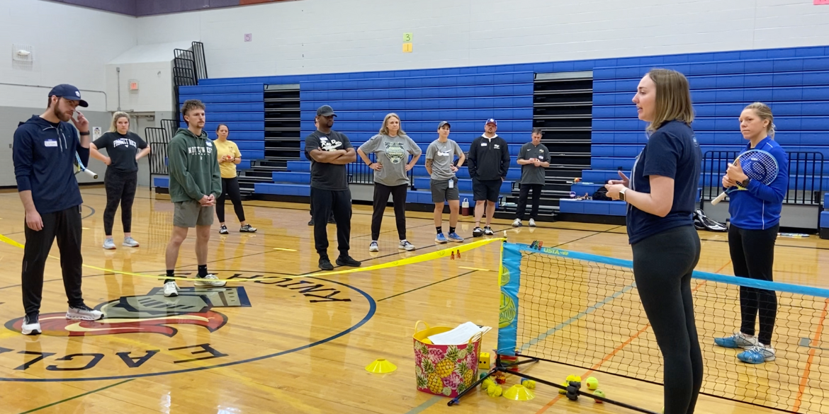 A photo of Rebecca Falkner Axelrod speaking to a group of PE teachers during their training to bring tennis into their school district.