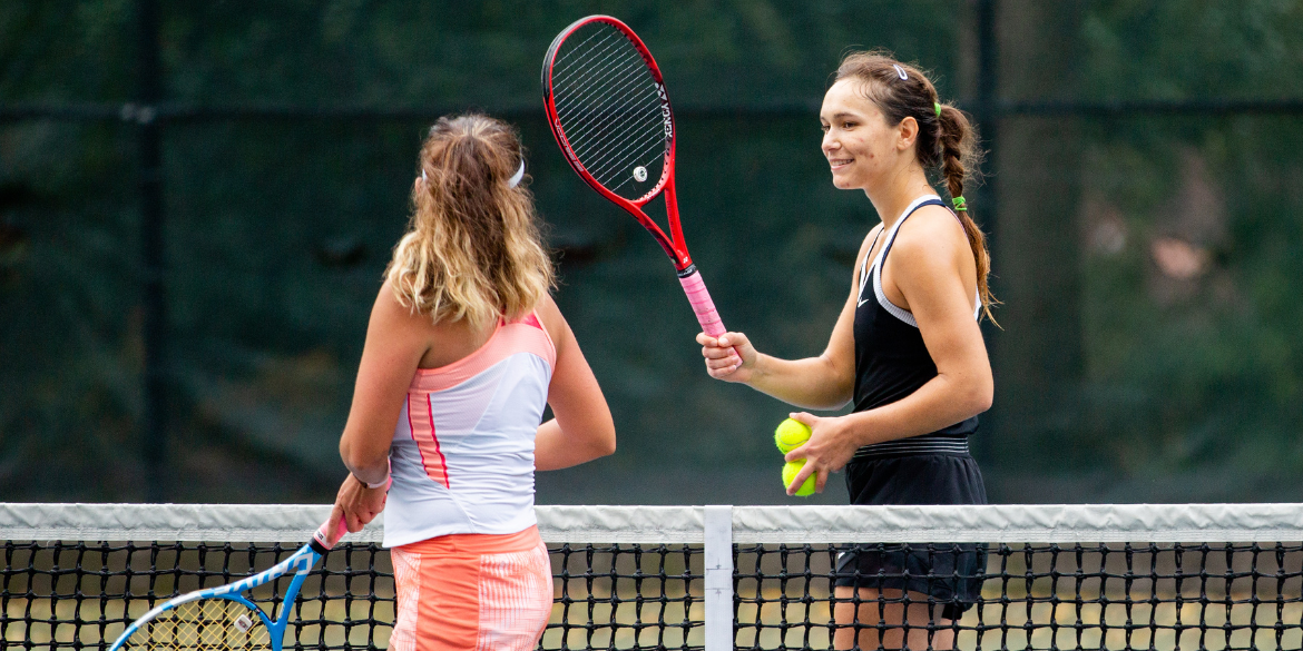 A photo of two women on a tennis court holding tennis racquets.